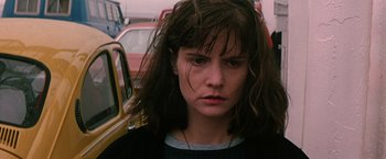 Movie still from “Dolores Claiborne” (1995), directed by Taylor Hackford – A woman with long brown hair standing in a parking lot next to cars; Close Up shot, Low angle