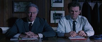 Movie still from “Dolores Claiborne” (1995), directed by Taylor Hackford – Two men sitting at a table in front of each other; Medium shot, Over the shoulder angle