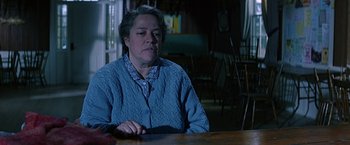 Movie still from “Dolores Claiborne” (1995), directed by Taylor Hackford – An older woman sitting at a table in a room; Medium shot, Over the shoulder angle