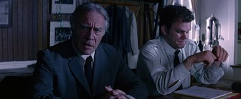 Movie still from “Dolores Claiborne” (1995), directed by Taylor Hackford – A man in a suit and tie sitting next to another man in a suit and tie; Medium shot, Over the shoulder angle