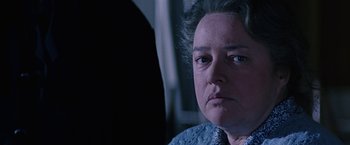 Movie still from “Dolores Claiborne” (1995), directed by Taylor Hackford – An older woman looking at the camera in a dark room; Close Up shot, Over the shoulder angle