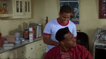 A man is getting his hair combed by another man