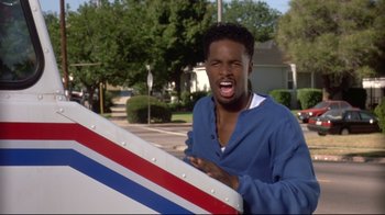 A young man holding onto a large object in the street