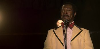 Movie still from “Dolemite Is My Name” (2019), directed by Craig Brewer – A man in a yellow jacket and a red bow tie; Close Up shot, Over the shoulder angle