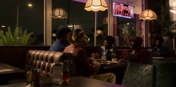 Movie still from “Dolemite Is My Name” (2019), directed by Craig Brewer – A group of people sitting at a table in a restaurant; Wide shot, Over the shoulder angle