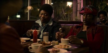 Movie still from “Dolemite Is My Name” (2019), directed by Craig Brewer – A group of people sitting at a table eating food; Medium shot, Over the shoulder angle