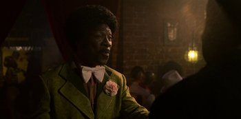 Movie still from “Dolemite Is My Name” (2019), directed by Craig Brewer – A man in a green suit with a flower in his hair; Close Up shot, Over the shoulder angle