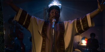Movie still from “Dolemite Is My Name” (2019), directed by Craig Brewer – A man with a microphone in front of a light; Medium shot, Low angle