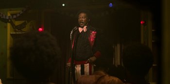 Movie still from “Dolemite Is My Name” (2019), directed by Craig Brewer – A man standing on a stage holding a microphone; Medium shot, Low angle