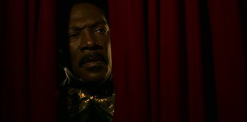 Movie still from “Dolemite Is My Name” (2019), directed by Craig Brewer – A man in a bow tie looking out from behind a red curtain; Close Up shot, Low angle