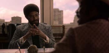 Movie still from “Dolemite Is My Name” (2019), directed by Craig Brewer – A man sitting at a table with another man in front of him; Medium shot, Over the shoulder angle