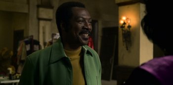 Movie still from “Dolemite Is My Name” (2019), directed by Craig Brewer – A man in a yellow shirt and green jacket smiling; Close Up shot, Over the shoulder angle