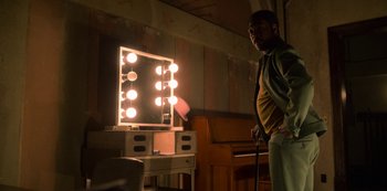 Movie still from “Dolemite Is My Name” (2019), directed by Craig Brewer – A man standing in front of a lighted mirror; Medium shot, Low angle