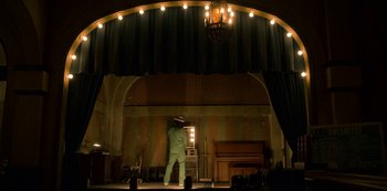 Movie still from “Dolemite Is My Name” (2019), directed by Craig Brewer – A man standing on a stage in front of a stage light; Wide shot, Low angle