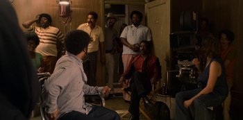 Movie still from “Dolemite Is My Name” (2019), directed by Craig Brewer – A group of men standing in a living room; Wide shot, Over the shoulder angle