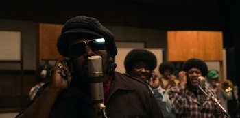 Movie still from “Dolemite Is My Name” (2019), directed by Craig Brewer – A group of people that are in a room with a microphone; Close Up shot, Low angle
