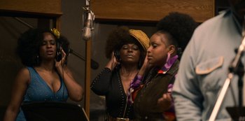 Movie still from “Dolemite Is My Name” (2019), directed by Craig Brewer – A woman in a yellow hat is listening to a microphone; Medium shot, Low angle