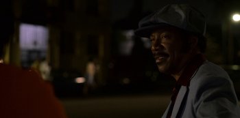 Movie still from “Dolemite Is My Name” (2019), directed by Craig Brewer – A man wearing a hat is smiling for the camera; Close Up shot, Over the shoulder angle