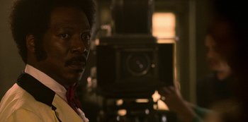 Movie still from “Dolemite Is My Name” (2019), directed by Craig Brewer – A man is taking a picture with a camera; Close Up shot, Over the shoulder angle