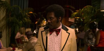 Movie still from “Dolemite Is My Name” (2019), directed by Craig Brewer – A man in a white suit and red bow tie; Medium shot, Over the shoulder angle