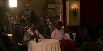 Movie still from “Dolemite Is My Name” (2019), directed by Craig Brewer – A group of men sitting at a table in a room; Wide shot, Over the shoulder angle