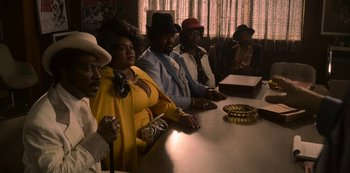 Movie still from “Dolemite Is My Name” (2019), directed by Craig Brewer – A group of people sitting at a table in front of a window; Wide shot, High angle