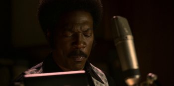 Movie still from “Dolemite Is My Name” (2019), directed by Craig Brewer – A man sitting in front of a microphone in a recording studio; Close Up shot, Low angle