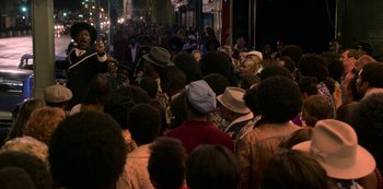 Movie still from “Dolemite Is My Name” (2019), directed by Craig Brewer – A crowd of people standing on a street at night; Medium shot, High angle