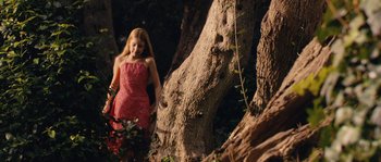Movie still from “Don't Look Back” (2009), directed by Marina de Van – A girl in a red dress in front of a tree; Wide shot, Low angle