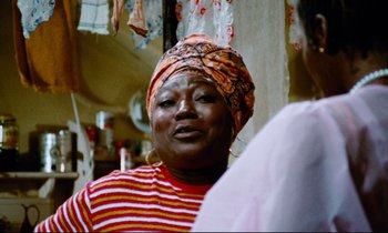 Movie still from “Don't Play Us Cheap” (1972), directed by Melvin Van Peebles – An older woman wearing a head scarf talking to another woman; Close Up shot, Low angle