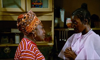 Movie still from “Don't Play Us Cheap” (1972), directed by Melvin Van Peebles – Two women are talking in a kitchen; Medium shot, Low angle