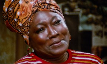 Movie still from “Don't Play Us Cheap” (1972), directed by Melvin Van Peebles – A person wearing a head scarf; Close Up shot, Low angle