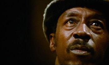 Movie still from “Don't Play Us Cheap” (1972), directed by Melvin Van Peebles – A person wearing a hat; Extreme Close Up shot, Low angle