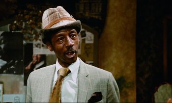 Movie still from “Don't Play Us Cheap” (1972), directed by Melvin Van Peebles – A man wearing a suit and a hat; Close Up shot, Low angle
