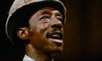 Movie still from “Don't Play Us Cheap” (1972), directed by Melvin Van Peebles – A person wearing a hat; Close Up shot, Low angle