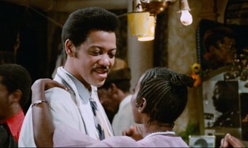Movie still from “Don't Play Us Cheap” (1972), directed by Melvin Van Peebles – A man and a woman are smiling at each other; Close Up shot, Low angle