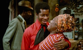 Movie still from “Don't Play Us Cheap” (1972), directed by Melvin Van Peebles – A man and a woman are hugging in a room; Medium shot, Over the shoulder angle