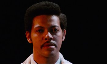 Movie still from “Don't Play Us Cheap” (1972), directed by Melvin Van Peebles – A person wearing a white shirt; Close Up shot, Low angle