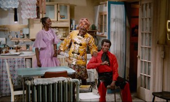 Movie still from “Don't Play Us Cheap” (1972), directed by Melvin Van Peebles – A group of three people in a room; Wide shot, High angle
