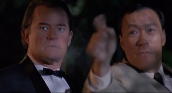Movie still from “Double Impact” (1991), directed by Sheldon Lettich – A man in a suit and tie next to another man in a suit and tie; Close Up shot, Low angle