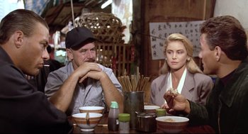 Movie still from “Double Impact” (1991), directed by Sheldon Lettich – A man and a woman sitting at a table with chopsticks in front of them; Medium shot, Over the shoulder angle