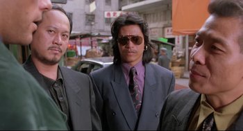 Movie still from “Double Impact” (1991), directed by Sheldon Lettich – A man in a suit and tie standing next to another man; Medium shot, Low angle