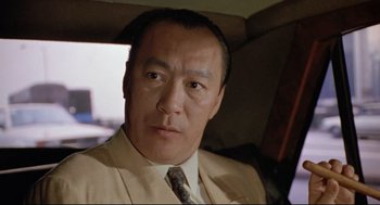 Movie still from “Double Impact” (1991), directed by Sheldon Lettich – A person wearing a suit and tie; Close Up shot, Low angle