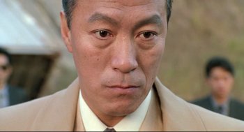 Movie still from “Double Impact” (1991), directed by Sheldon Lettich – A person wearing a suit and tie; Close Up shot, Low angle