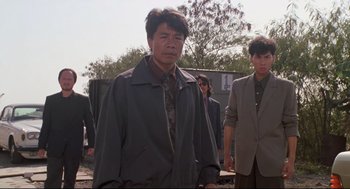 Movie still from “Double Impact” (1991), directed by Sheldon Lettich – A group of men standing next to each other on a field; Medium shot, Low angle