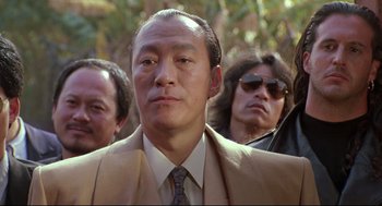 Movie still from “Double Impact” (1991), directed by Sheldon Lettich – A group of men standing next to each other in a forest; Close Up shot, Low angle