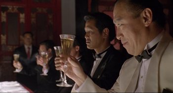 Movie still from “Double Impact” (1991), directed by Sheldon Lettich – A group of people sitting at a table with drinks; Medium shot, Low angle