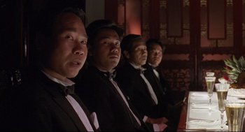 Movie still from “Double Impact” (1991), directed by Sheldon Lettich – A group of men standing next to each other in suits; Medium shot, Low angle