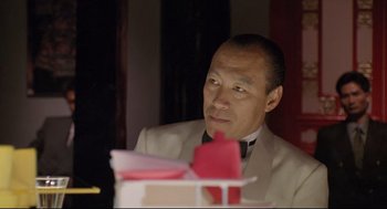 Movie still from “Double Impact” (1991), directed by Sheldon Lettich – A man sitting at a dinner table in a restaurant; Close Up shot, Low angle