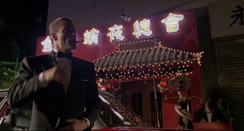 Movie still from “Double Impact” (1991), directed by Sheldon Lettich – A man in a tuxedo standing in front of an asian restaurant; Medium shot, Low angle